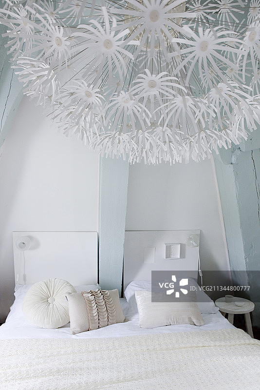 卧室内的白色双人床与浅蓝色光束，前景是浪漫的灯图片素材