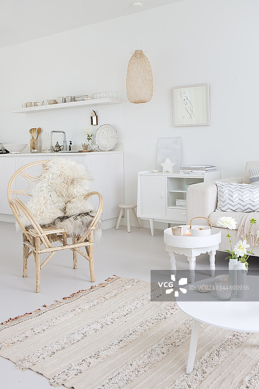 白色客厅中的藤椅、羊皮地毯、桌子和餐具柜图片素材