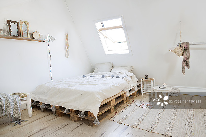 斜屋顶下自然色调的卧室，配有托盘床图片素材