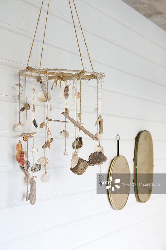贝壳和浮木制成的手机挂饰，白色木板墙背景图片素材