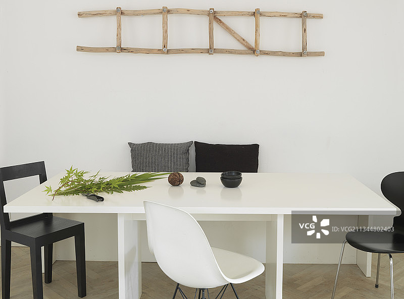 餐桌上方墙壁上的装饰木梯与黑白椅子图片素材