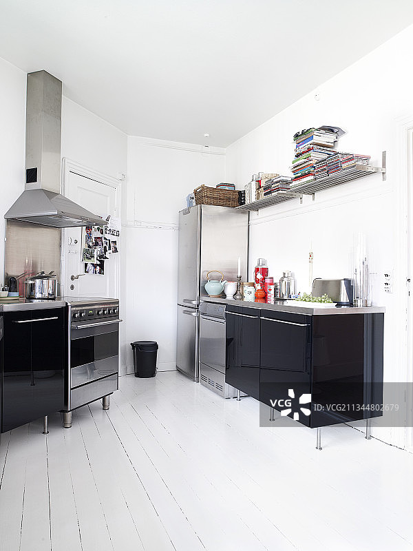 带有不锈钢台面的黑色高光厨房，位于带有白色木地板的旧建筑中图片素材