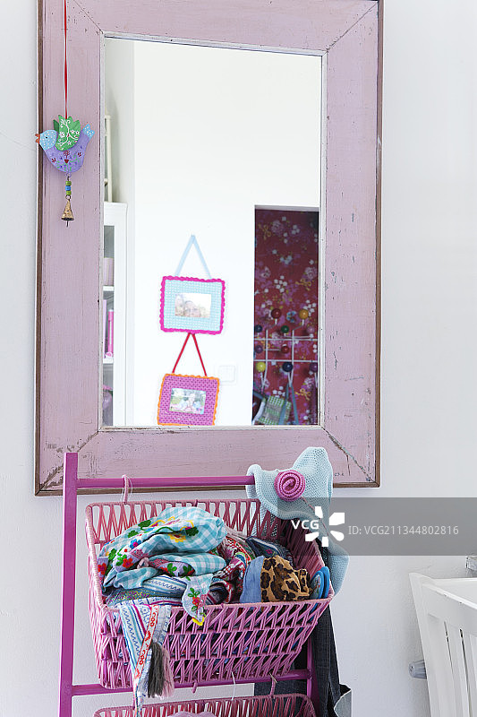 带毛巾的粉色篮子，位于带粉色木制框架的墙镜前图片素材