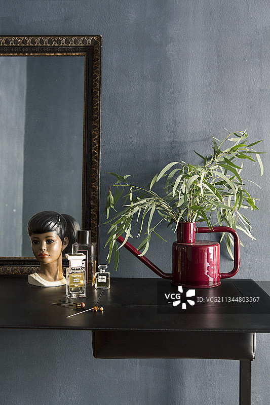 红色浇水壶用作花瓶，梳妆台上摆放复古半身像图片素材