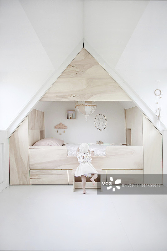 孩子爬进阁楼卧室的现代小床，周围都是储物空间图片素材