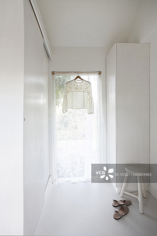 白色内饰中挂在带通风窗帘的窗户上的漂亮衬衫图片素材