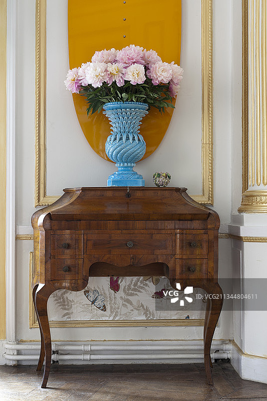 蓝色花瓶中的牡丹花，背景是镶板墙图片素材