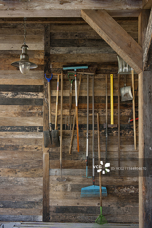 悬挂在再生木板墙上的园艺工具图片素材