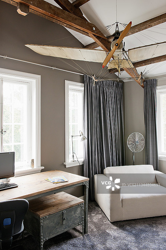 悬挂在工业风格桌子上方的模型飞机图片素材