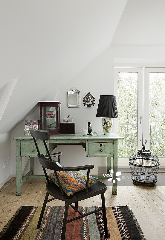 倾斜天花板下薄荷绿色桌子旁的黑色椅子图片素材