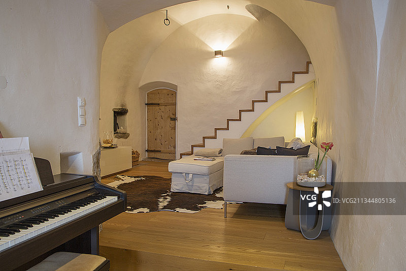 带拱形天花板和楼梯的乡村风客厅中的钢琴图片素材