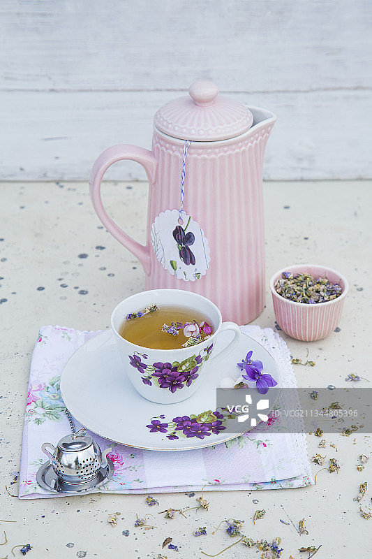 花卉茶杯和保温茶壶中的紫罗兰花茶图片素材