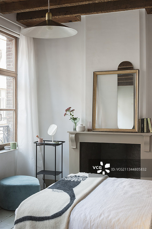 卧室里的双人床、壁炉和壁炉架上的镜子图片素材