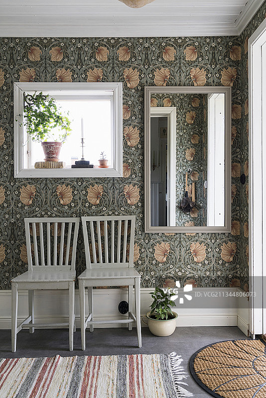 走廊墙壁上威廉·莫里斯花卉壁纸镜子下的两把椅子图片素材