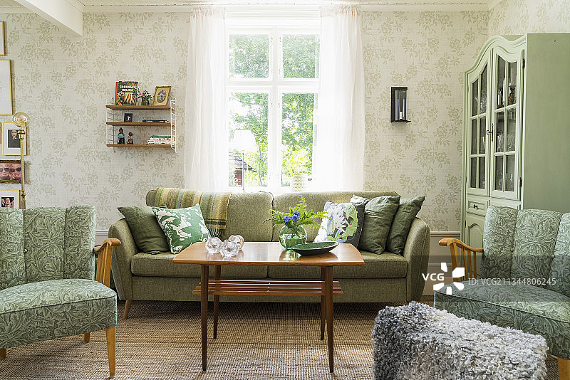 客厅里绿色的软垫家具、梳妆台和带有图案的壁纸图片素材