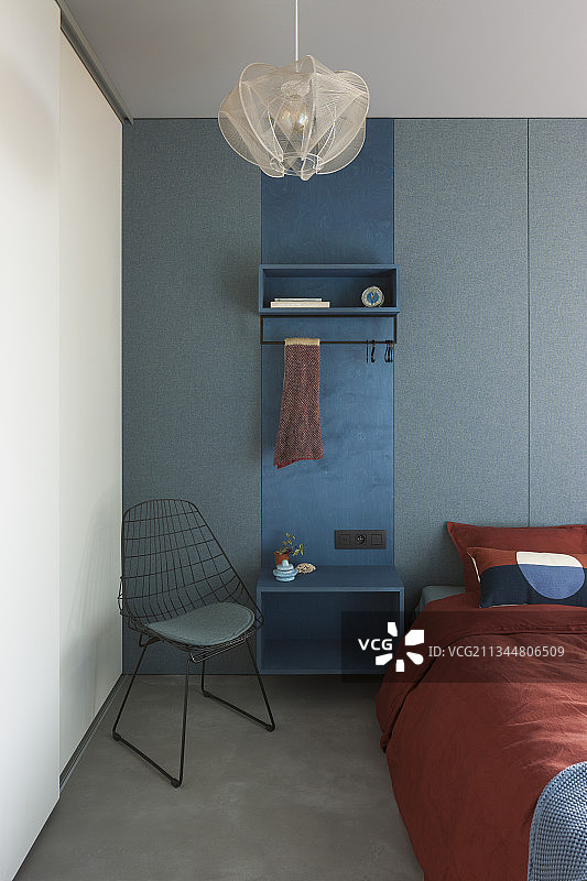 蓝色衣帽间面板用作床和金属椅之间的床头柜图片素材