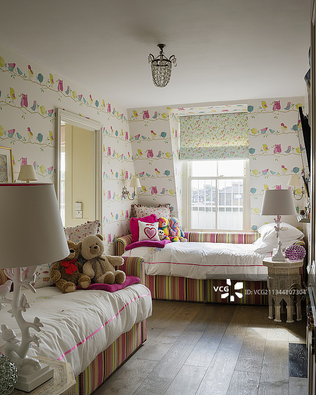 儿童卧室里带有条纹框架的双人床，墙纸是小鸟图案图片素材