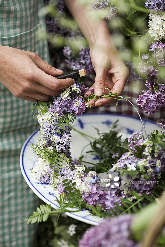 女人编织丁香花和簇绒野豌豆花环图片素材