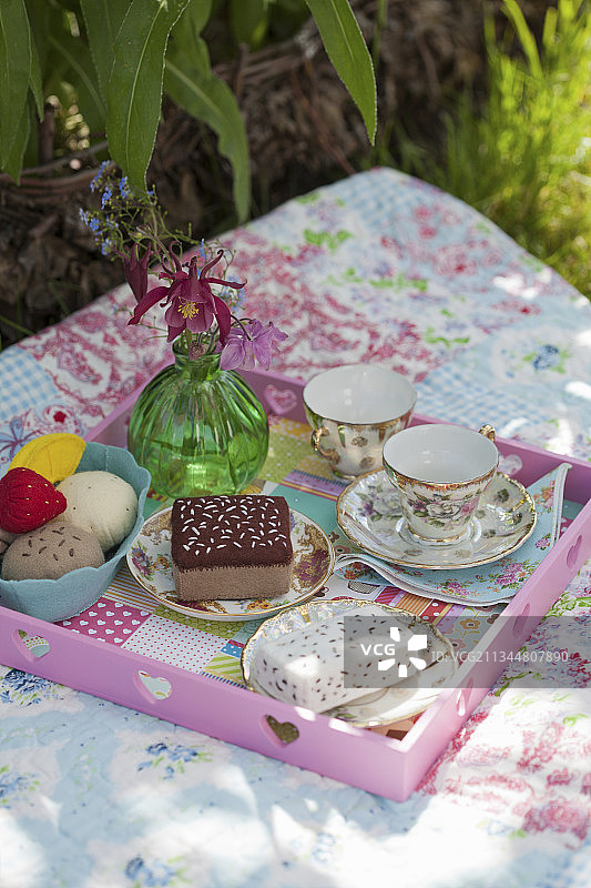 野餐毯上的手工毛毡蛋糕、冰淇淋和瓷茶杯图片素材