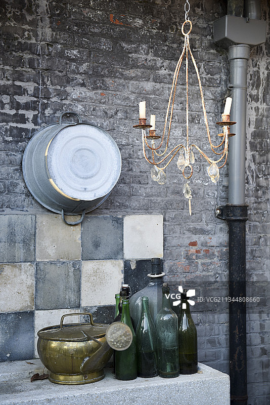 砖墙背景下的老旧玻璃瓶和石制水槽上的喷壶图片素材