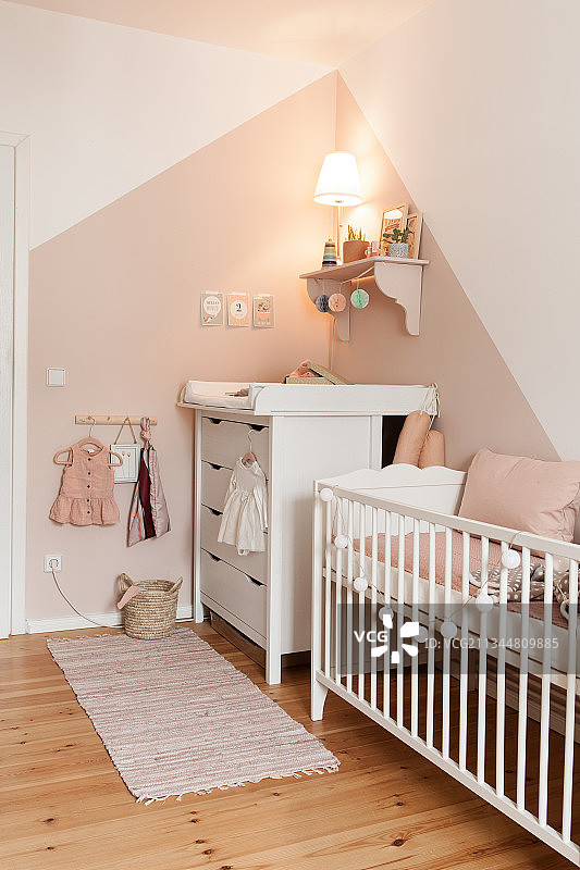 粉色和白色婴儿房中的婴儿床和换尿布台图片素材