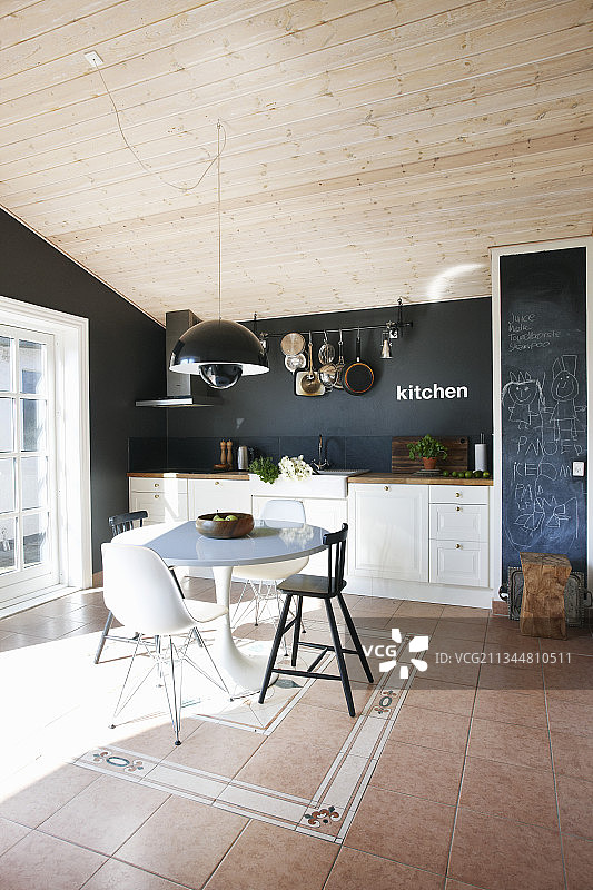白色厨房内的早餐桌，配有各种椅子，背景是黑色墙壁图片素材