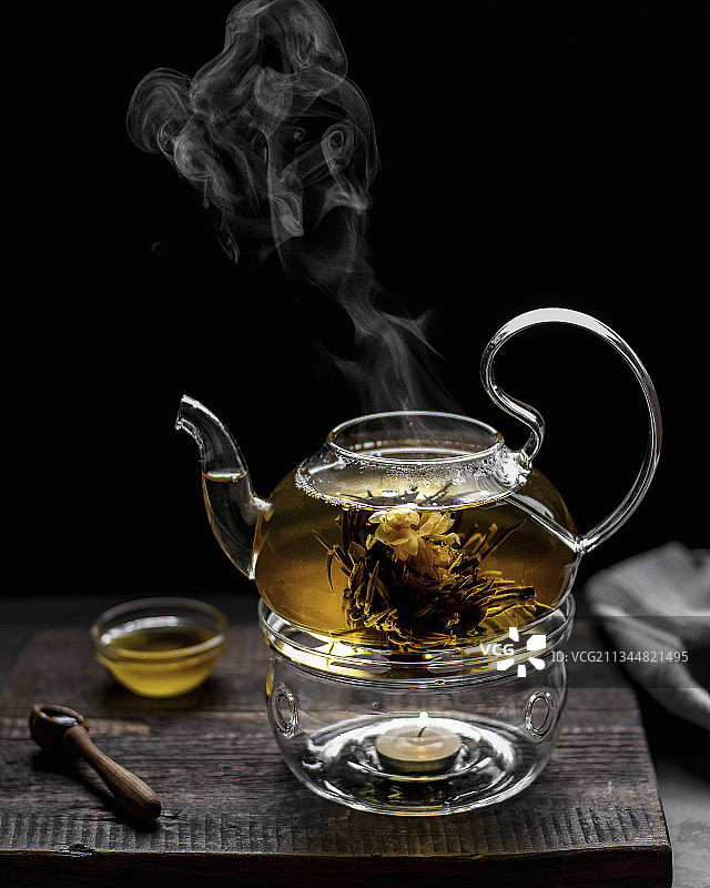 黑色背景下，玻璃茶壶在加热器上的花茶图片素材