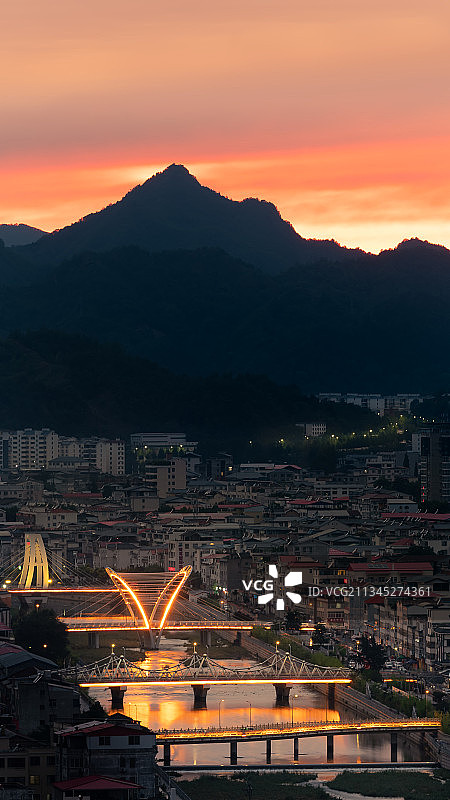 火烧云下的小城中河道上面有好多桥都亮着暖光图片素材