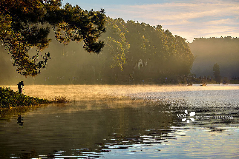 日落时分在湖中钓鱼的男子轮廓，泰国曼谷图片素材