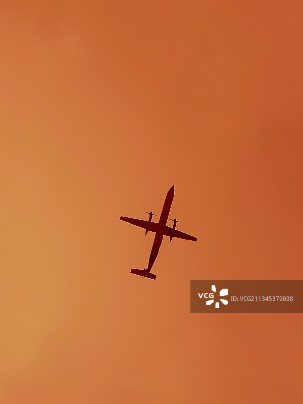 仰视：飞机飞过橙色天空图片素材