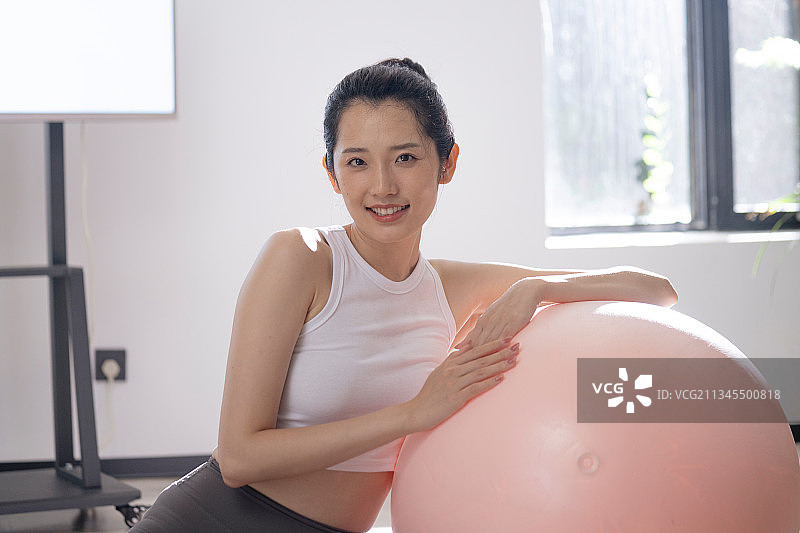 青年女孩抱着瑜伽球冲着镜头笑图片素材