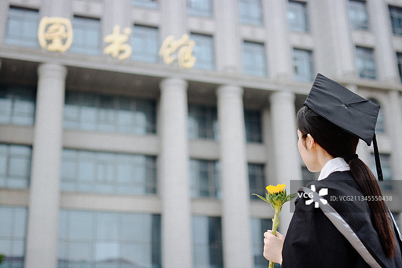 图书馆前大学毕业学士服手捧向日葵渴望知识图片素材
