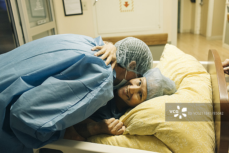丈夫在医院安慰正在接受剖腹产的妻子图片素材