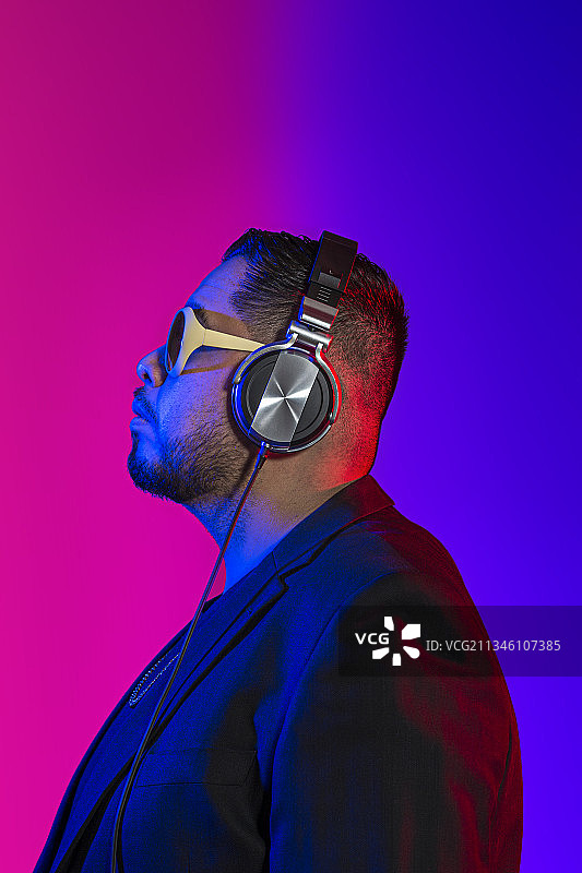 一位俱乐部DJ的侧面像，彩色背景图片素材