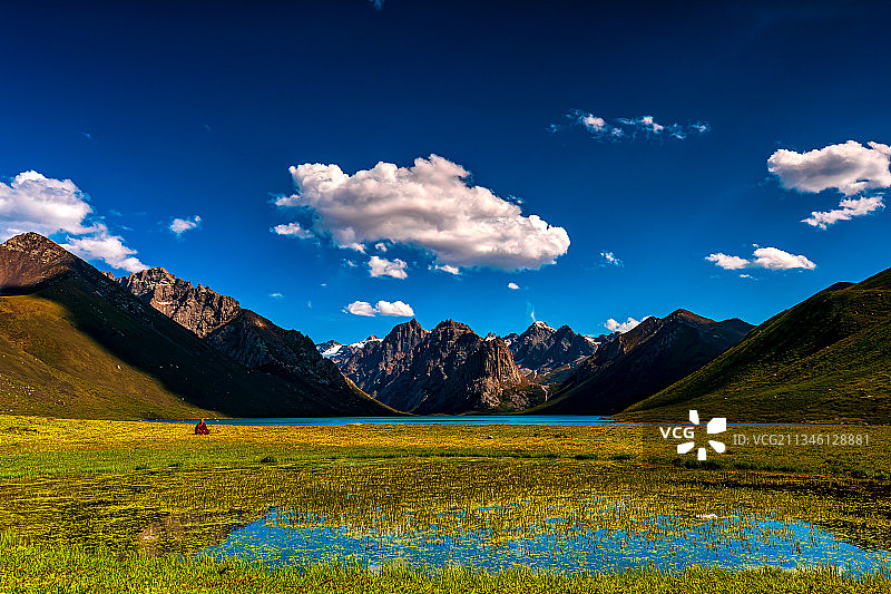 7月的年保玉则，天空祥云朵朵，雪山之下仙女湖畔草地茂密。图片素材