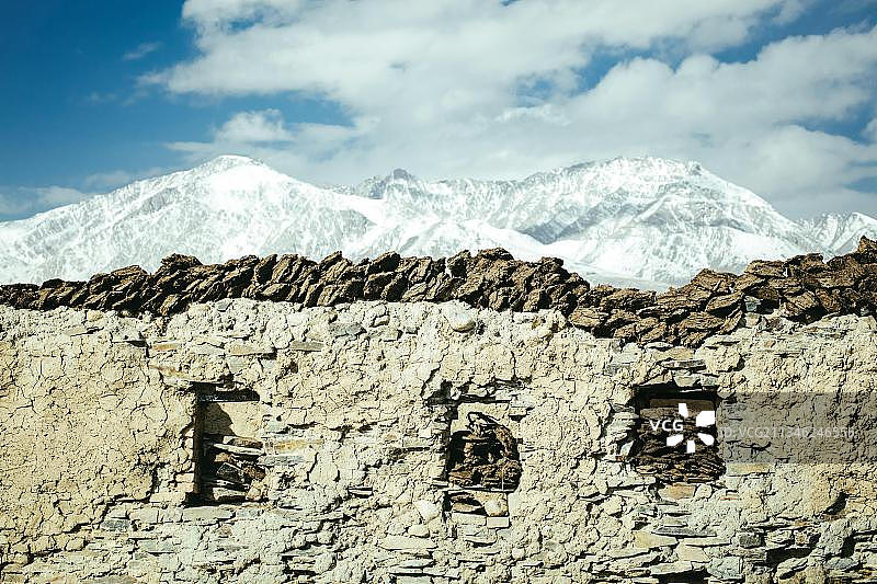 石头和粘土制成的马厩，位于阿富汗瓦罕走廊的博扎伊贡巴兹，背景是兴都库什山脉的雪峰图片素材