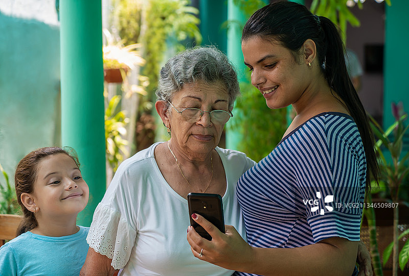 年轻女人向老妇人和女孩展示手机，古巴圣克拉拉图片素材