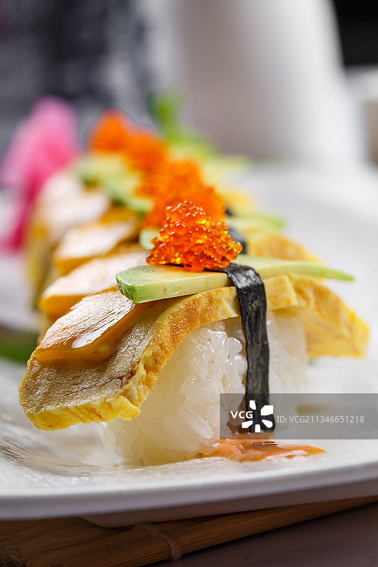 烧蛋蟹子芒果手握寿司摆放在寿司帘上图片素材