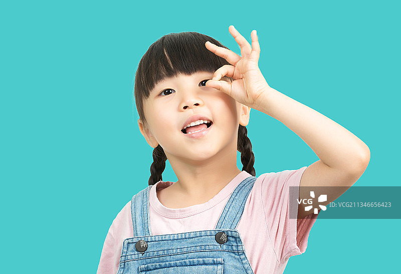 柔色背景前做ok手势的可爱小女孩图片素材