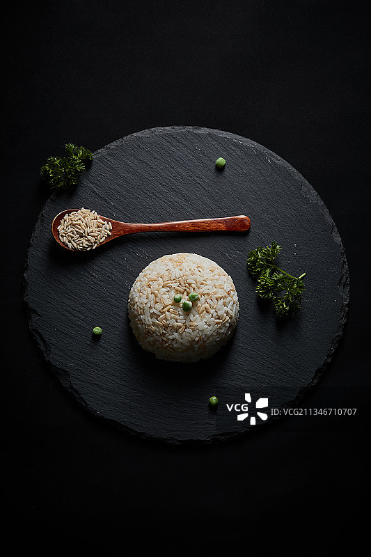 黑色青石板上的燕麦米大米混合蒸制的米饭及粥图片素材