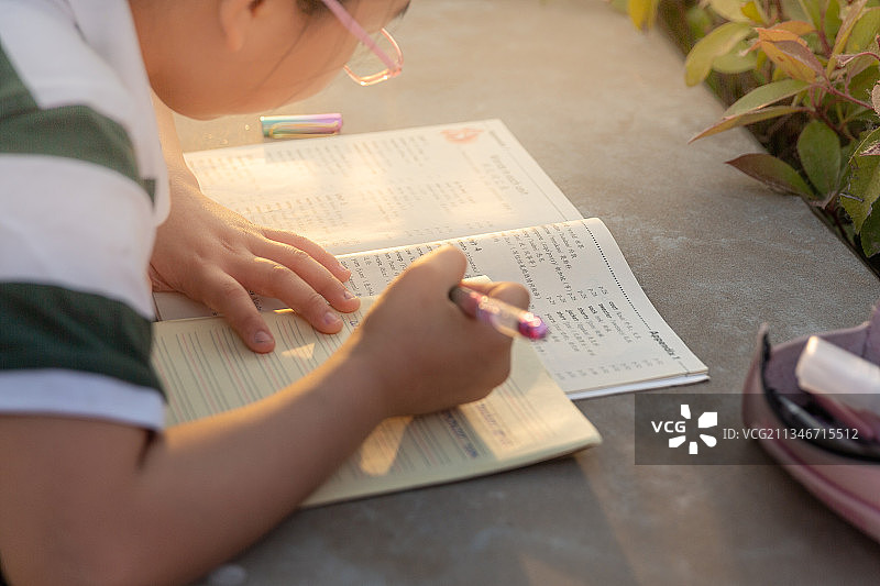 小学生趴在路边石桌上写作业图片素材