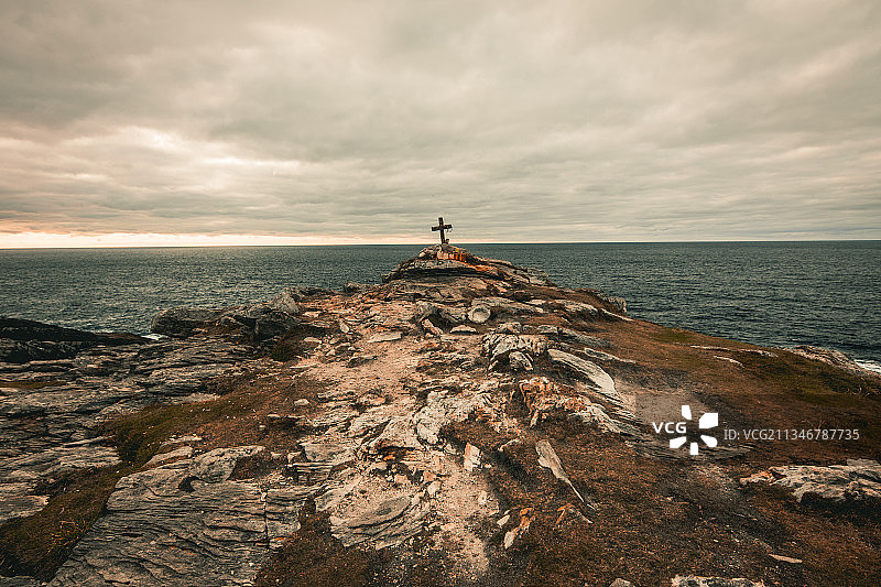 男子站在爱尔兰阿德马林海边的岩石上，背景是多云的天空图片素材