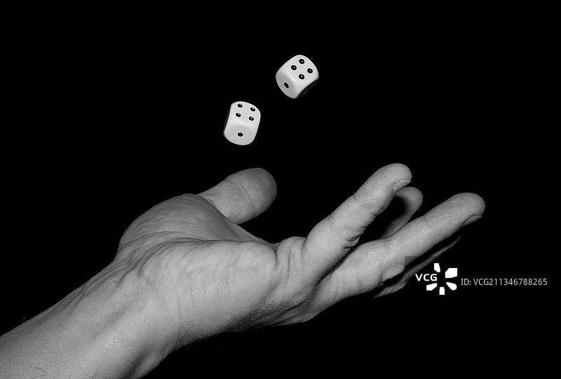 手持骰子的照片，黑色背景图片素材