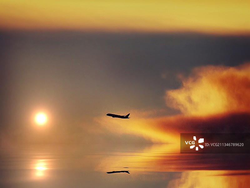 日落时分飞机飞过天空的剪影的低角度景观图片素材