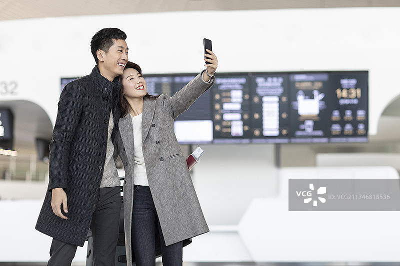 年轻夫妇在机场使用手机自拍图片素材