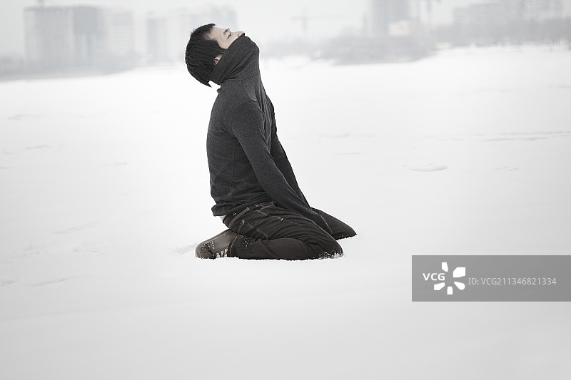 绝望的男人独自坐在雪地里，仰望天空图片素材