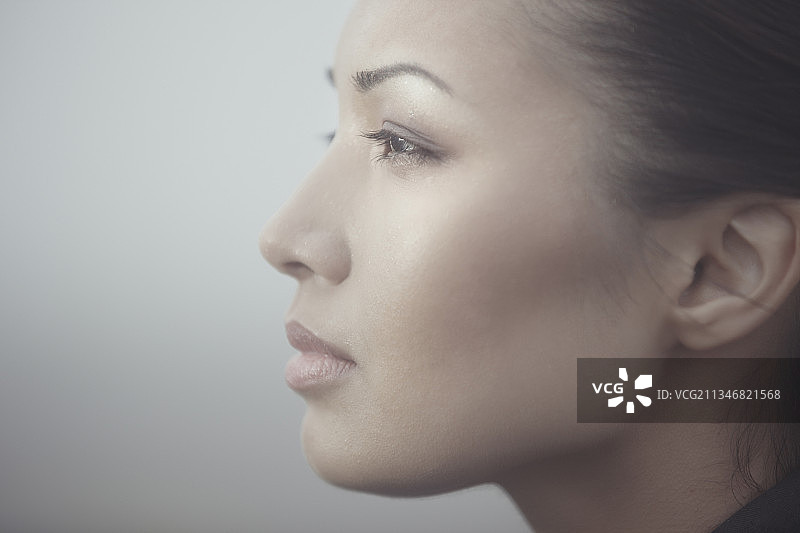 在雾气弥漫区域沉思的亚洲女人侧影。图片素材