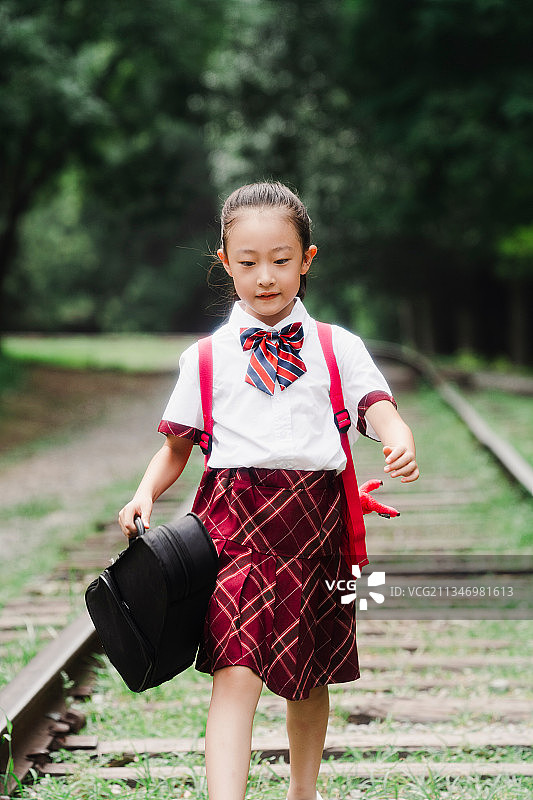 小学生提着小提琴盒在户外图片素材