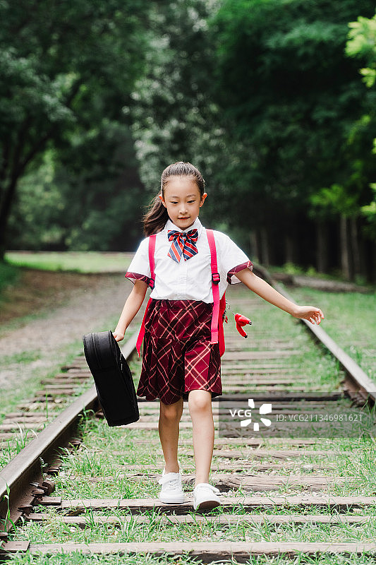 小学生提着小提琴盒在户外图片素材