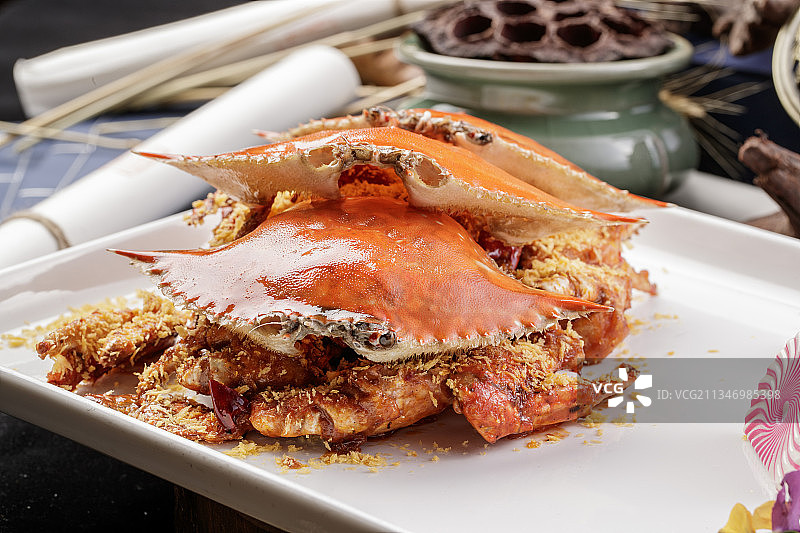 长方形瓷盘装的避风塘炒蟹摆放在黑色背景上图片素材